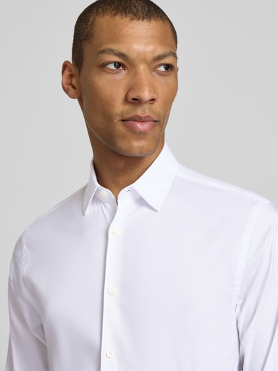 Męski model nosi Extra Slim Fit Business-Koszulę z kołnierzykiem typu kent model 'BRODIE' od Tiger of Sweden, listwa guzikowa, długość tyłu w rozmiarze 40: 73 cm, szerokość ramion w rozmiarze 40: 45 cm, długość rękawów w rozmiarze 40: 67 cm, biała, gładka faktura, zbliżenie na górną część ciała.