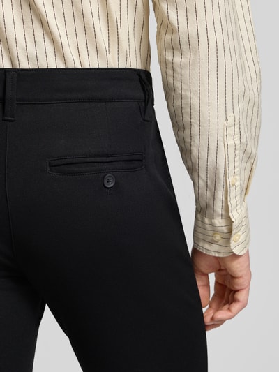 Männermodel trägt Slim Fit Stoffhose aus Viskose-Mix Modell 'MARK' von Only & Sons, schwarzer Anzug-Stoff, Detailaufnahme Rückansicht, Eingrifftaschen, Knopfverschluss, Viskose-Elasthan-Mix, Kontext: Bundweite 43 cm, Innenbeinlänge 78 cm bei Größe 32/32.