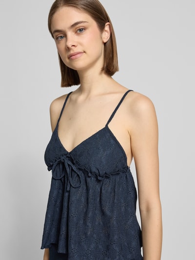 Modelka nosi Babydoll-Top mit Schößchendetail und Lochstickerei von REVIEW, granatowy kolor, mieszanka materiałów z dodatkiem streczu, krój regular fit, baskinka, haft angielski, długość tyłu w rozmiarze S: 27 cm, zbliżenie na górną część ciała z przodu.