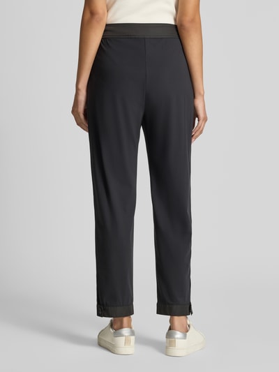 Frauenmodel trägt Bundfaltenhose in Two-Tone-Machart von Marc Cain, Relaxed Fit, Material-Mix mit Stretch, schwarze Farbe, Ganzkörperansicht Rückansicht.