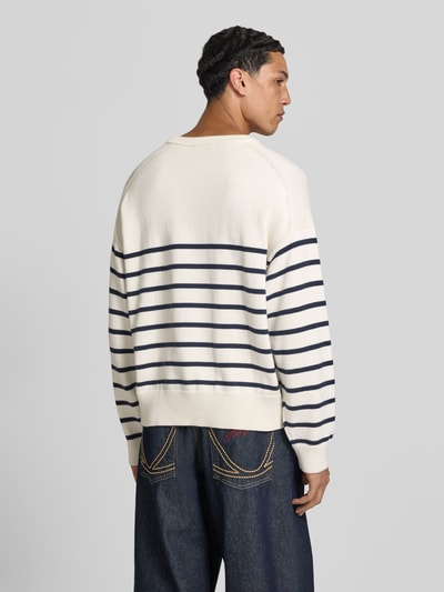 Männermodel trägt Regular Fit Strickpullover aus reiner Baumwolle von Calvin Klein Jeans in gestreifter gebreide look, lange mouw, ronde hals, logo-applicatie, ribboorden, puur katoen materiaal, Ganzkörperansicht Rückansicht.