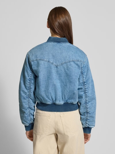 Vrouwenmodel draagt Bomberjacke mit Stehkragen und Reißverschluss Modell 'SCOUT' van Levi's®, regular fit, lichtblauw denim, opgestikte klepzakken, ribboord aan kraag, zoom en manchetten, lengte 53 cm, schouderbreedte 45 cm, borstwijdte 48 cm, mouwlengte 60 cm, achteraanzicht hele lichaam