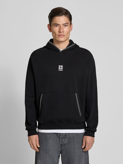 Männermodel trägt Regular Fit Hoodie aus reiner Baumwolle Modell 'DAROHOOD' von HUGO, schwarz unifarben, Kängurutasche, Ganzkörperansicht von vorne.