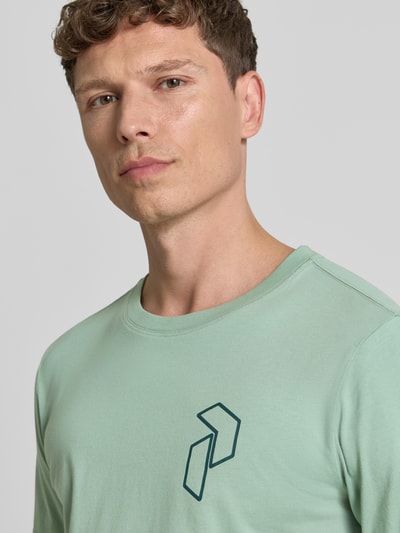 Männermodel trägt T-Shirt mit Label-Print und Rundhalsausschnitt von PEAK PERFORMANCE in Mintgrün, reine Baumwolle, Nahaufnahme Oberkörper.