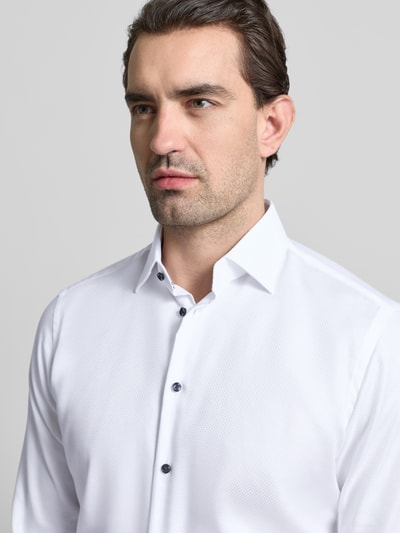 Männermodel trägt Regular Fit Business Hemd aus Baumwolle mit Kentkragen von Christian Berg Men, weiße Textur, Nahaufnahme Oberkörper.