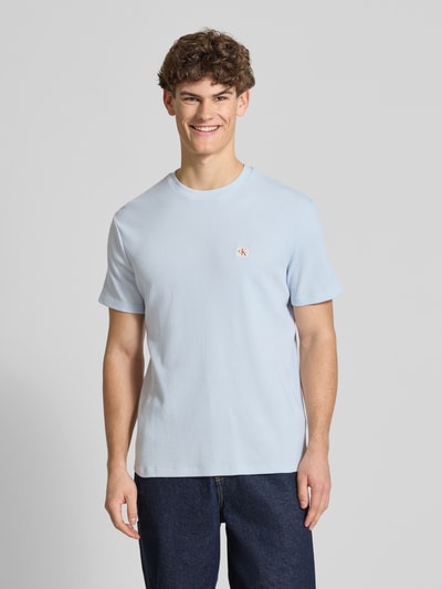 Männermodel trägt Regular Fit T-Shirt mit Logo-Patch von Calvin Klein Jeans, hellblau, Baumwoll-Mix, Strukturmuster, Rundhalsausschnitt, Rückenlänge 68 cm bei Größe M, Ganzkörperansicht von vorne.