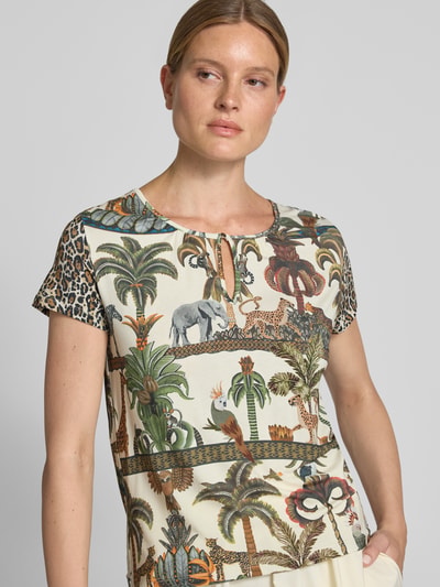 Frauenmodel trägt T-Shirt aus Viskose-Elasthan-Mix mit Schlüsselloch-Ausschnitt von MORE & MORE im Allover-Look, Nahaufnahme Oberkörper.