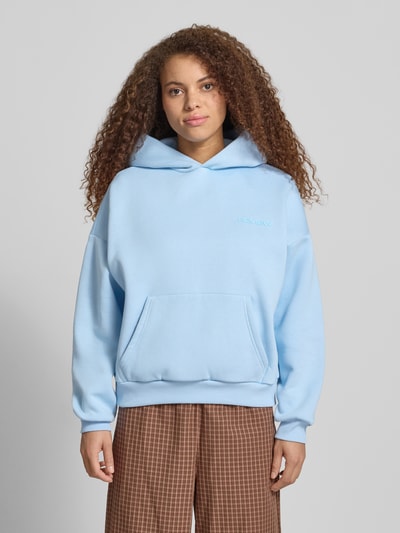 Frauenmodel trägt Hoodie mit Logo-Print und Känguru-Tasche von REVIEW aus Baumwoll-Mix, Loose-Fit, Kapuze, Ganzkörperansicht von vorne.