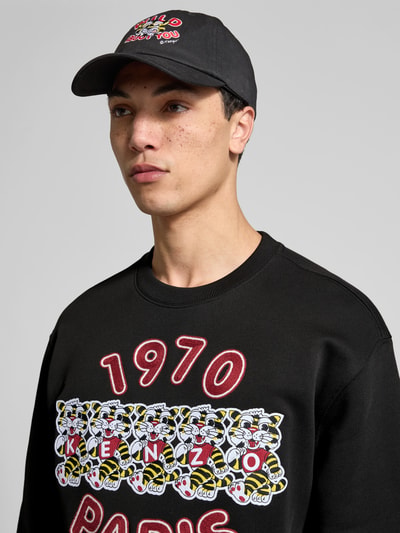 Männermodel trägt Sweatshirt aus reiner Baumwolle von Kenzo in Schwarz mit Label-Print, lockerer Passform, Rundhalsausschnitt, elastischen Abschlüssen; Nahaufnahme Oberkörper.