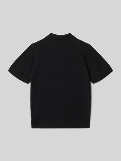 Vrouwenmodel draagt Regular Fit Poloshirt in Strick-Optik Modell 'Max' van Jack & Jones, zwart, katoen, kort. Achteraanzicht, Ganzkörperansicht.