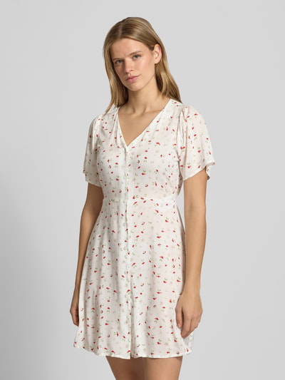 Frauenmodel trägt Minikleid aus reiner Viskose Modell 'EVIDA' von Only, Optik: Allover-Muster, tailliert, Mini-Länge, V-Ausschnitt, Knopfleiste, Taillengürtel, Kurzarm, Material: reine Viskose, helle Grundfarbe mit zarten Mustern, glatte Textur, Ganzkörperansicht von vorne.