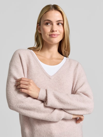 Modelka kobieca nosi sweter z dzianiny z mieszanką lnu, efekt prążkowania, dekolt w serek, luźny krój, Model 'DAMSVILLE' od American Vintage, długość tyłu 61 cm, długość rękawów 54 cm, jasnoróżowe odcienie, miękka faktura, zbliżenie na górną część ciała