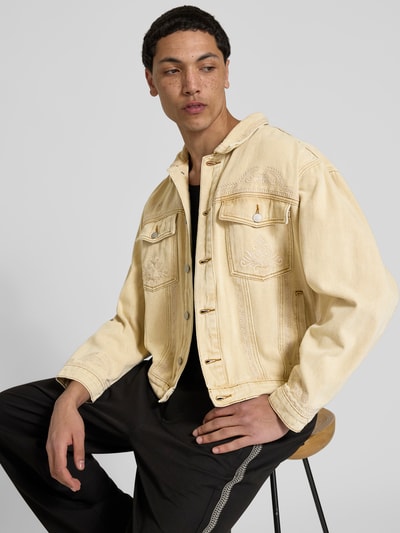Männermodel trägt Jeansjacke mit Brusttaschen von Don’t Waste Culture aus Reine Baumwolle, Regular-Fit, Kentkragen, durchgängige Knopfleiste, helle Beige- und Cremetöne, sichtbare Nähte, glatte Struktur, Rückenlänge 64 cm, Schulterbreite 53 cm, Ärmellänge 60 cm, Ganzkörperansicht von vorne.