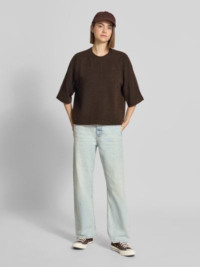 Kobiece model prezentuje sweter o kroju regular fit z rękawami o dł. 3/4 model 'SIMONI' od ONLY w kolorze ciemnobrązowym, jasnoniebieskie dżinsy, pełny widok z przodu, sweter damski ONLY