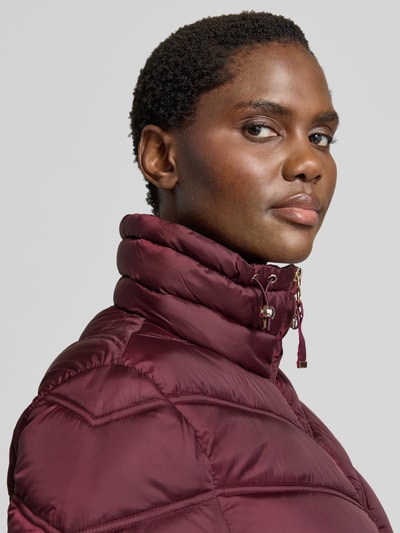 Vrouwenmodel draagt Steppjacke mit Stehkragen und Reißverschlusstaschen van Christian Berg Woman Selection in bordeaux, gladde textuur, regular fit, ritssluiting en ritszakken, detailopname schouder en kraag.