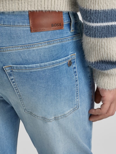 Männermodel trägt Slim Fit Jeans aus Baumwoll-Mix Modell 'ONYX' von BOSS, Denim in Hellblau, Logo-Applikation, Nahaufnahme Rückansicht.