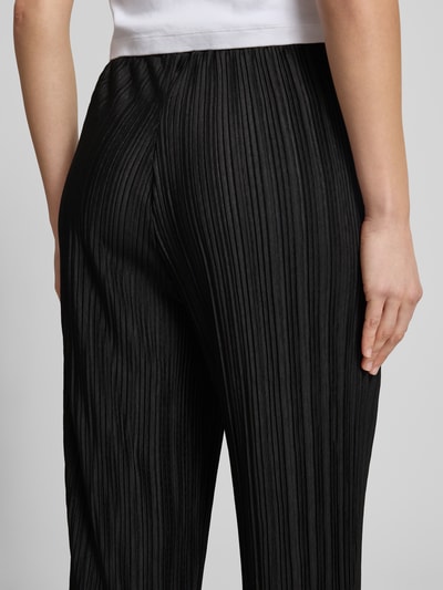 Frauenmodel trägt schwarze Stoffhose mit Plisseefalten Modell 'MIKALA' von ICHI im Material-Mix mit Stretch-Anteil, Nahaufnahme Rückansicht.