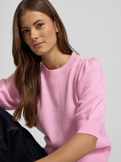 Frauenmodel trägt Regular Fit Strickpullover mit Crew Neck Modell 'DOFFY' von Vero Moda in Rosa, Strickoptik, Nahaufnahme Oberkörper.
