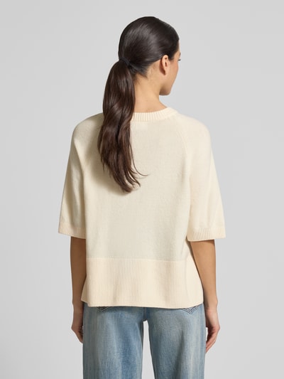 Frauenmodel trägt Strickpullover mit 1/2-Arm von Comma aus Baumwoll-Mix mit Stretch-Anteil, Relaxed-Fit, Rundhalsausschnitt, Rückenlänge 52 cm, Ärmellänge 13 cm, hellbeige mit feiner Strickstruktur und breiten Bündchen, Ganzkörperansicht Rückansicht.