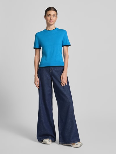 Modelka nosi Strickshirt aus Leinen-Mix in Two-Tone-Machart od Stefanel, krój slim fit, okrągły dekolt, długość tyłu 54 cm, rękaw 20 cm, intensywny niebieski z czarnymi detalami, gładka tekstura, dziewczęcy styl, cała sylwetka z przodu.