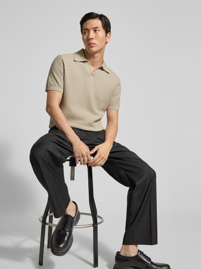 Männermodel trägt Poloshirt mit Polokragen und V-Ausschnitt von JAKE*S STUDIO MEN in Beige zu schwarzer Hose, Nahaufnahme Oberkörper.