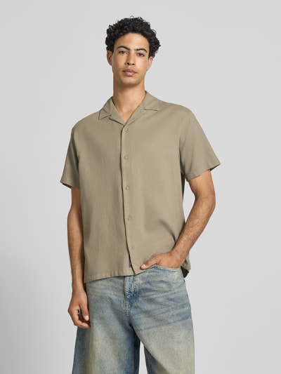 Męski model nosi koszulę casualową Regular Fit Freizeithemd mit Strukturmuster Modell 'Global' von Jack & Jones z bawełny, z krótkim rękawem, kołnierzem z połami, z fakturowanym wzorem, listwą guzikową na całej długości, długość tyłu w rozmiarze M: 71 cm, szerokość ramion w rozmiarze M: 51 cm, długość rękawa w rozmiarze M: 25 cm, kolor beżowy, gładka faktura, prosty krój, Ganzkörperansicht von vorne.