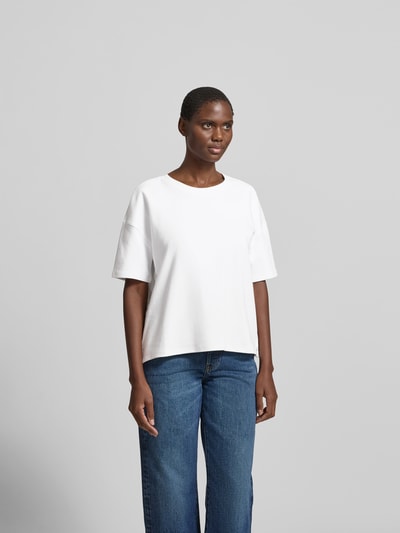 Frauenmodel trägt Regular Fit T-Shirt aus Baumwoll-Mix von Juvia in Weiß mit Rundhalsausschnitt, Halbarm, überschnittenen Schultern, Ganzkörperansicht von vorne.