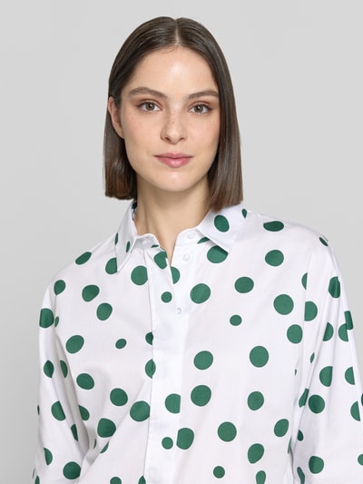 Frauenmodel trägt Relaxed Fit Hemdbluse mit 3/4-Arm von Christian Berg Woman, weiße Reine Baumwolle mit grünen Punkten, Hemdblusenkragen, durchgängige Knopfleiste, Rückenlänge bei Größe 36: 57 cm, Ärmellänge 65 cm, Nahaufnahme Oberkörper.