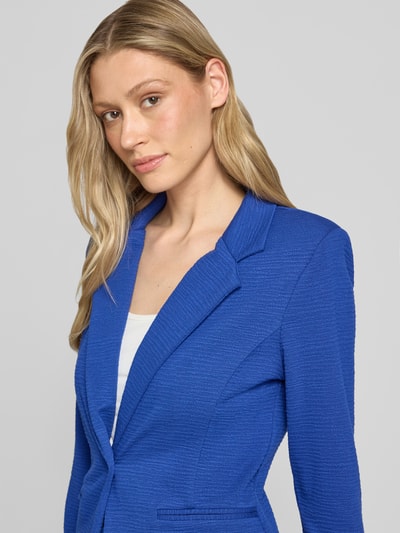 Frauenmodel trägt Slim Fit Blazer aus Viskose-Mix Modell 'KATE LUMINA' von ICHI in Blau mit Reverskragen, Knopfverschluss, Paspeltaschen, Nahaufnahme Oberkörper. Kontext: Damen Blazer, Viskose-Mix mit Stretch-Anteil, Slim Fit, Rückenlänge bei Größe S 59 cm, Brustweite 43 cm, Ärmellänge 49 cm.