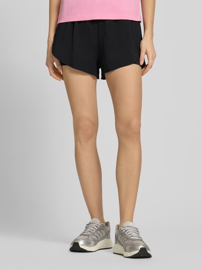 Frauenmodel trägt Regular Fit Shorts mit Reißverschlusstaschen von adidas Sportswear im 2-in-1-Look, elastischer Bund, schwarze Farbe, Ganzkörperansicht von vorne.