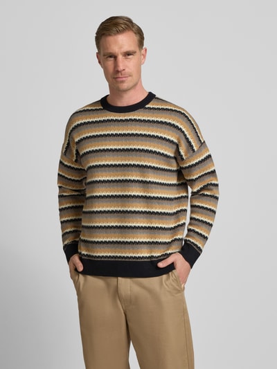 Männermodel trägt Strickpullover mit Rundhalsausschnitt Modell 'Neelio' von Drykorn im Baumwoll-Woll-Mix, Relaxed-Fit, Ganzkörperansicht von vorne.
