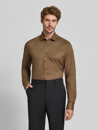 Männermodel trägt Body Fit Businesshemd mit extra langem Arm von OLYMP in Braun, glatte Oberfläche, klassische Knopfleiste, Ganzkörperansicht von vorne, Herren Businesshemd von OLYMP Level 5.
