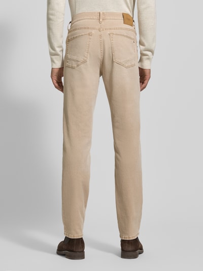 Männermodel trägt Slim Fit Jeans mit 5-Pocket-Design Modell 'Chuck' von Brax, Baumwoll-Elasthan-Mix, hellbeige, Ganzkörperansicht Rückansicht.