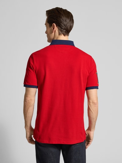 Männermodel trägt Regular Fit Poloshirt aus reiner Baumwolle von Polo Ralph Lauren, unifarbenes Rot, Piqué-Textur, Ganzkörperansicht Rückansicht.