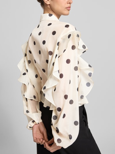 Vrouwenmodel draagt Regular Fit strikblouse met Rüschen model 'DOROTHY' van Vero Moda, all-over polkadots, semi-transparant, lange ballonmouwen, elastische mouwboord, knoopsluiting, ganzebody achteraanzicht.