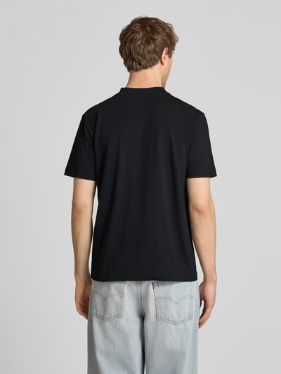Męski model nosi czarny t-shirt z wyhaftowanym logo ACCIANO CLASSIC od Ellesse, bawełna, prosty krój, stójka, długość tyłu 67 cm, całkowity widok z tyłu.