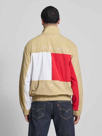 Männermodel trägt Regular Fit Blouson mit Logo-Stitching von Tommy Hilfiger in Beige, Rot und Weiß, Satinstruktur, Ganzkörperansicht Rückansicht.