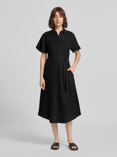 Frauenmodel trägt Midikleid aus Viskose-Mix mit Umlegekragen von COMMA in Schwarz, tailliert, kurze Ärmel, Ganzkörperansicht von vorne.