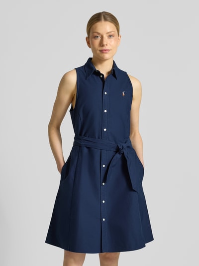 Vrouwenmodel draagt Regular Fit Polokleid aus reiner Baumwolle van Polo Ralph Lauren, look: effen, knielang, hooggesloten, tailleriem, mouwloos, materiaal: puur katoen, applicatie met gestikt logo, knoopsluiting. Ganzlicham zicht van voren.