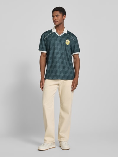 Männermodel trägt Regular Fit T-Shirt mit Logo-Stitching von MCNEAL in Dunkelgrün, Umlegekragen mit V-Ausschnitt, Kurzärmelig, Herren T-Shirt, Rückenlänge bei Größe M 71 cm, Ganzkörperansicht von vorne.