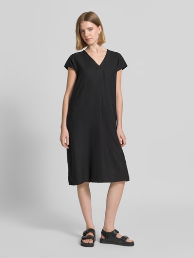 Frauenmodel trägt Knielanges Leinenkleid mit V-Ausschnitt Modell 'Ina' von Soyaconcept im Leinen-Mix mit Viskose-Anteil, Loose-Fit, Schwarz, seitliche Schlitze, Ganzkörperansicht von vorne.