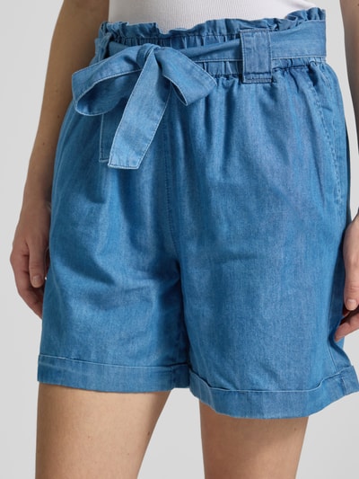Frauenmodel trägt Relaxed Fit Jeansshorts aus Baumwoll-Lyocell-Mix Modell 'BEA SMILLA' von Only in Denim-Optik mit Bindegürtel, Nahaufnahme Oberkörper.
