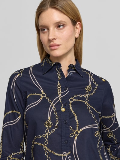 Vrouwenmodel draagt Regular Fit Bluse im Allover-Look van Gant in donkerblauw met goud patroon, pure katoen, hemdblousekraag, knoopsluiting, allover-look, maat 36 ruglengte 66 cm, mouwlengte 61 cm, detailopname bovenlichaam.