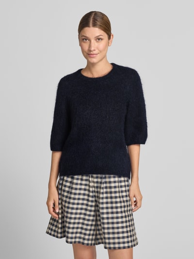 Kobieta nosi sweter z dzianiny z mieszanki moheru i bawełny Model 'debbie' od Gestuz, krój regular fit, okrągły dekolt, rękaw o dł. 1/2, długość tyłu w rozmiarze S: 47 cm, długość rękawów w rozmiarze S: 41 cm, ciemnogranatowy, prosta faktura, widoczne szerokie kratkowane szorty, zdjęcie typu: całkowity widok z przodu.