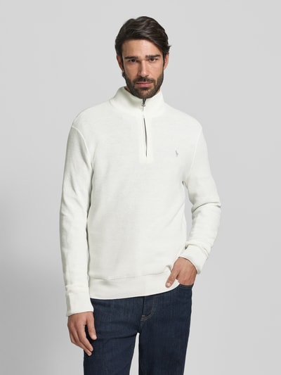 Männermodel trägt Strickpullover mit Label-Stitching von Polo Ralph Lauren in Weiß, reine Baumwolle, Regular-Fit, Stehkragen, kurzer Reißverschluss, gerippte Abschlüsse, Ganzkörperansicht von vorne.