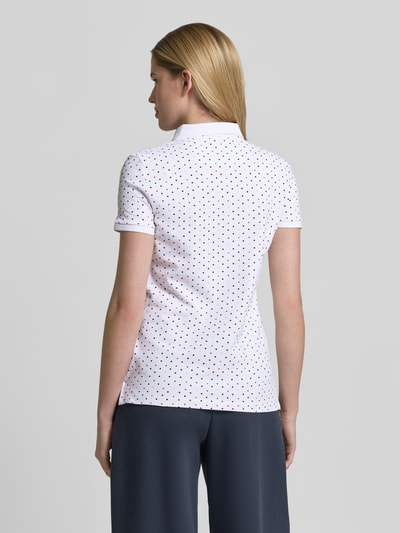 Modelka nosi Slim Fit Poloshirt mit Baumwoll-Anteil von Christian Berg Woman, wzór w drobne kropki, biały kolor, krój slim fit, mieszanka bawełny i elastanu, krótki rękaw, polokołnierzyk, długość pleców w rozmiarze S: 61 cm, widok całej sylwetki z tyłu.