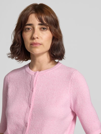 Vrouwenmodel draagt lichtroze regular fit gebreid jack met korte mouwen, Regular Fit Strickjacke mit kurzem Arm model 'VMDOFFY' van VERO MODA, Nahaufnahme bovenlichaam.