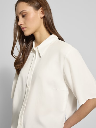 Frauenmodel trägt Relaxed Fit Bluse aus reinem Lyocell von Marc O'Polo Denim, weiß, Hemdkragen, kurzarm, unifarben, Nahaufnahme Oberkörper.