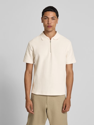 Männermodel trägt Regular Fit Poloshirt aus Baumwolle von Closed in Beige mit Strukturmuster, Polokragen und Reißverschluss, Kurzarm, Ganzkörperansicht von vorne.