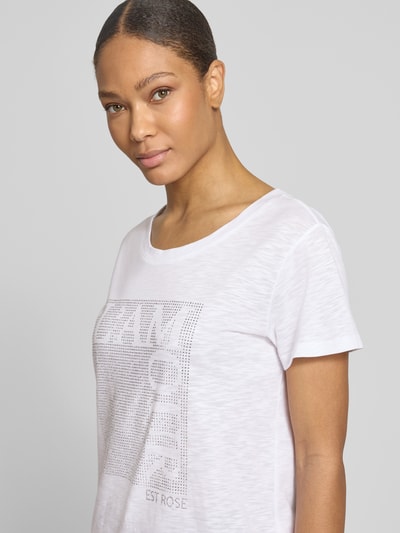Frauenmodel trägt T-Shirt mit Ziersteinbesatz und Rundhalsausschnitt von monari, Baumwoll-Micromodal-Mix, Regular-Fit, Nahaufnahme Oberkörper. Rückenlänge bei Größe 36: 58 cm.